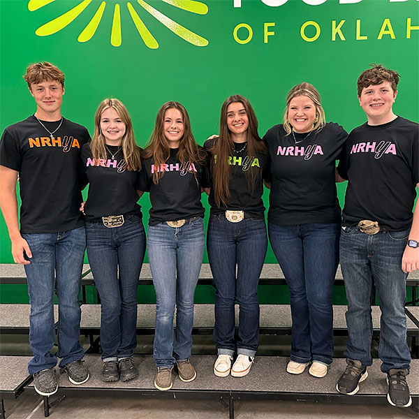 Six teenagers wearing NRHyA shirts standing and smiling in front of a green wall.